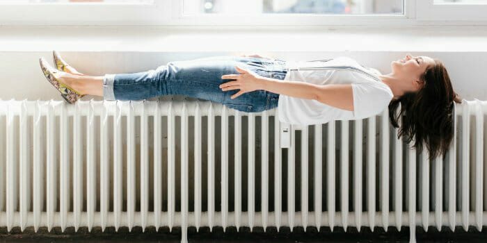 Eine lächelnde Frau liegt ausgestreckt auf einer Heizung