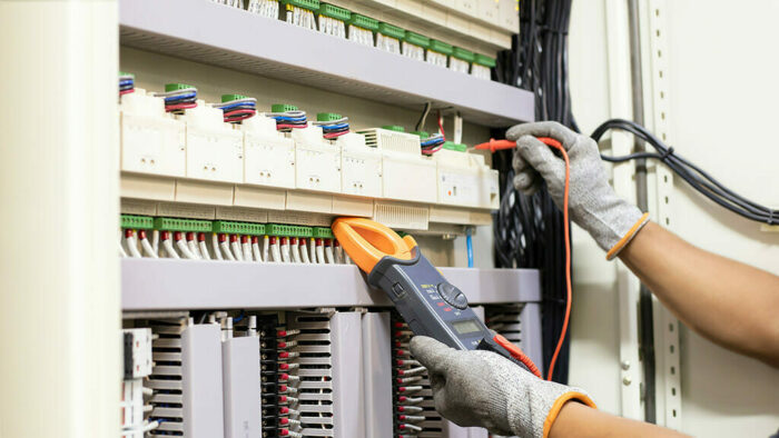 Ein Handwerker platziert Kabel an einem Schaltschrank