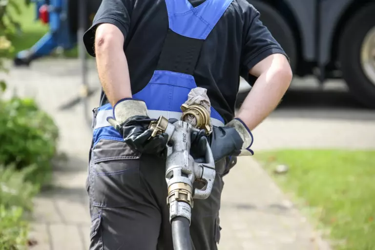 Mitarbeiter zieht Füllstutzen für Öl hinter sich her
