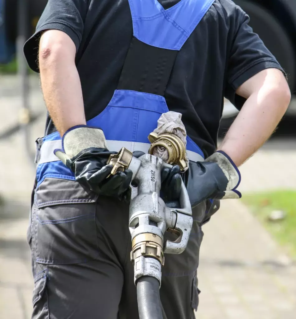 Mitarbeiter zieht Füllstutzen für Öl hinter sich her